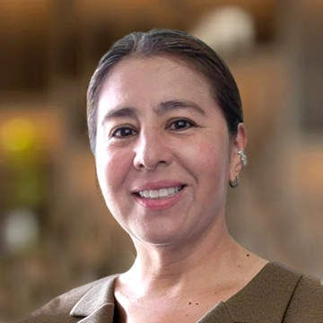 Smiling person in professional attire indoors.